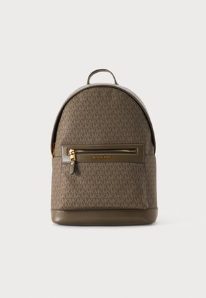 Mochila marrón Michael Kors con cremallera dorada y logo en el bolsillo delantero, parte superior redondeada y base de cuero sobre fondo claro.