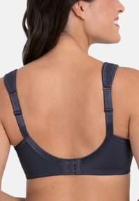 Donkergrijs beha met brede verstelbare banden, een gladde textuur en een haak-en-oogsluiting aan de achterkant. Eenvoudig, naadloos ontwerp.