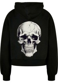 Sudadera corta negra con un gran gráfico de calavera pixelada en la parte trasera. La calavera presenta una textura agrietada y un sombreado detallado.