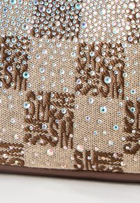 Μπεζ ύφασμα με καφέ κεντημένα ανθικά σχέδια διακοσμημένα με διάσπαρτους μικρούς και μεσαίους ιριδίζοντες στρας.