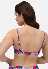 Top de bikini con estampado floral colorido y tirantes ajustables, que cuenta con un cierre de gancho en la parte posterior y un acabado de tela texturizada.
