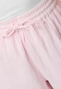 Pantaloni in cotone rosa chiaro con texture, dotati di una vita elastica e un laccio regolabile frontale. Tessuto morbido e traspirante con una vestibilità comoda.