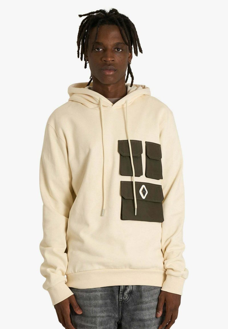 Felpa beige con un motivo frontale che presenta tre tasche verde scuro e una tasca inferiore più grande. Cappuccio con coulisse e polsini a costine.