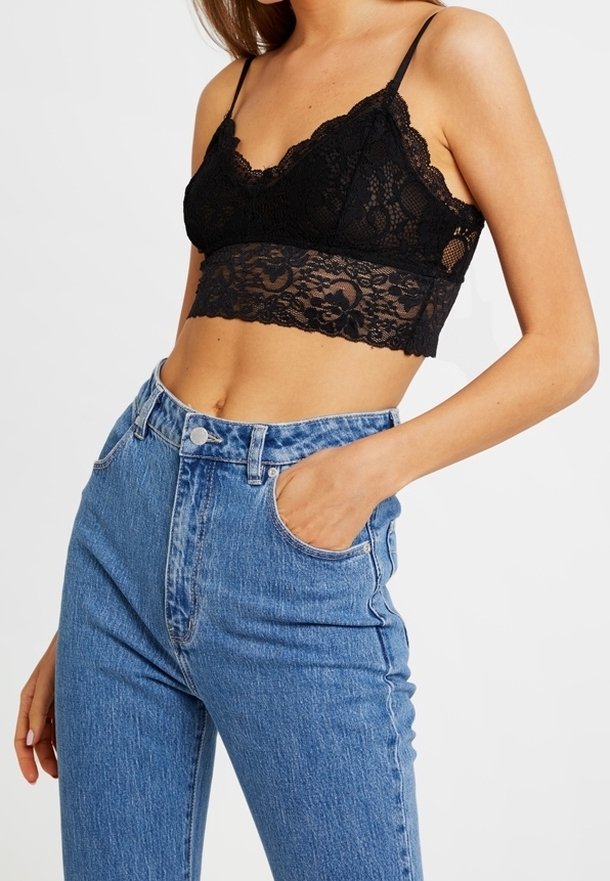Bralette en dentelle noire avec bords festonnés et bretelles réglables, associée à un jean en denim bleu taille haute, à la fois classique et doté de poches avant.