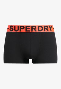 Boxer shorts neri in cotone con un ampio elastico arancione con testo "SUPERDRY" in nero. Texture liscia e vestibilità aderente.