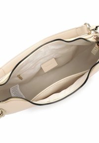 Inderside af beige lædertaske med lynlåslukning, der har en enkelt lomme og en glat foring. Fremhævet med detaljer i sort lynlås.