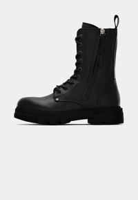 Zwarte leren combatboot met dikke zool, vetersluiting aan de voorkant, ritssluiting aan de zijkant en een trekhaak aan de achterkant, weergegeven vanuit de buitenkant.