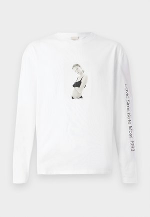 Bílý dlouhý rukáv tričko vyrobené z bavlny, s černobílou fotkou vepředu a textem na rukávu v černé barvě.