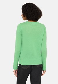 Pull vert clair en matière douce, avec un col rond et des manches longues à poignets et ourlet côtelés.