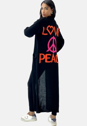 Cardigan lungo nero con "LOVE" in arancione e "PEACE" in rosa lavorato a maglia sul retro. Presenta tasche, una texture morbida e una vestibilità rilassata.