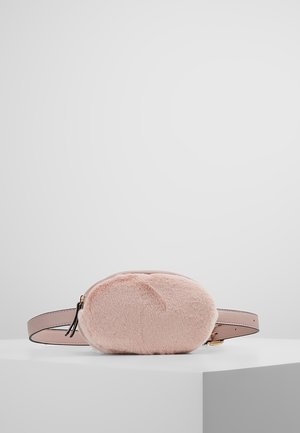 Sac ceinture ovale en fausse fourrure rose clair avec une sangle ajustable en cuir lisse et une fermeture éclair sur une surface blanche minimaliste.
