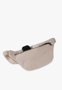 Beige fabric fanny pack with a zippered closure, featuring a smooth texture and an adjustable strap, partially filled with small items.
