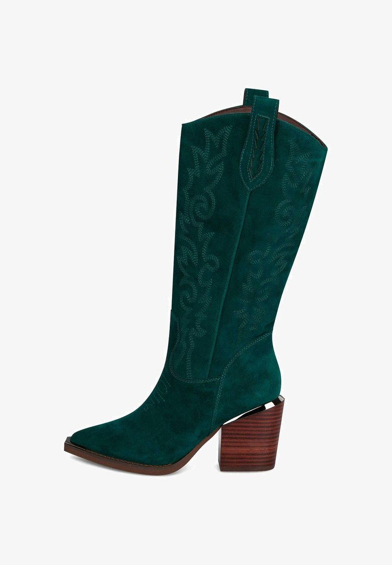 Bota vaquera verde de ante con punta afilada, costuras detalladas y un tacón de bloque de madera. Cuenta con una lengüeta en la parte superior para facilitar el uso.