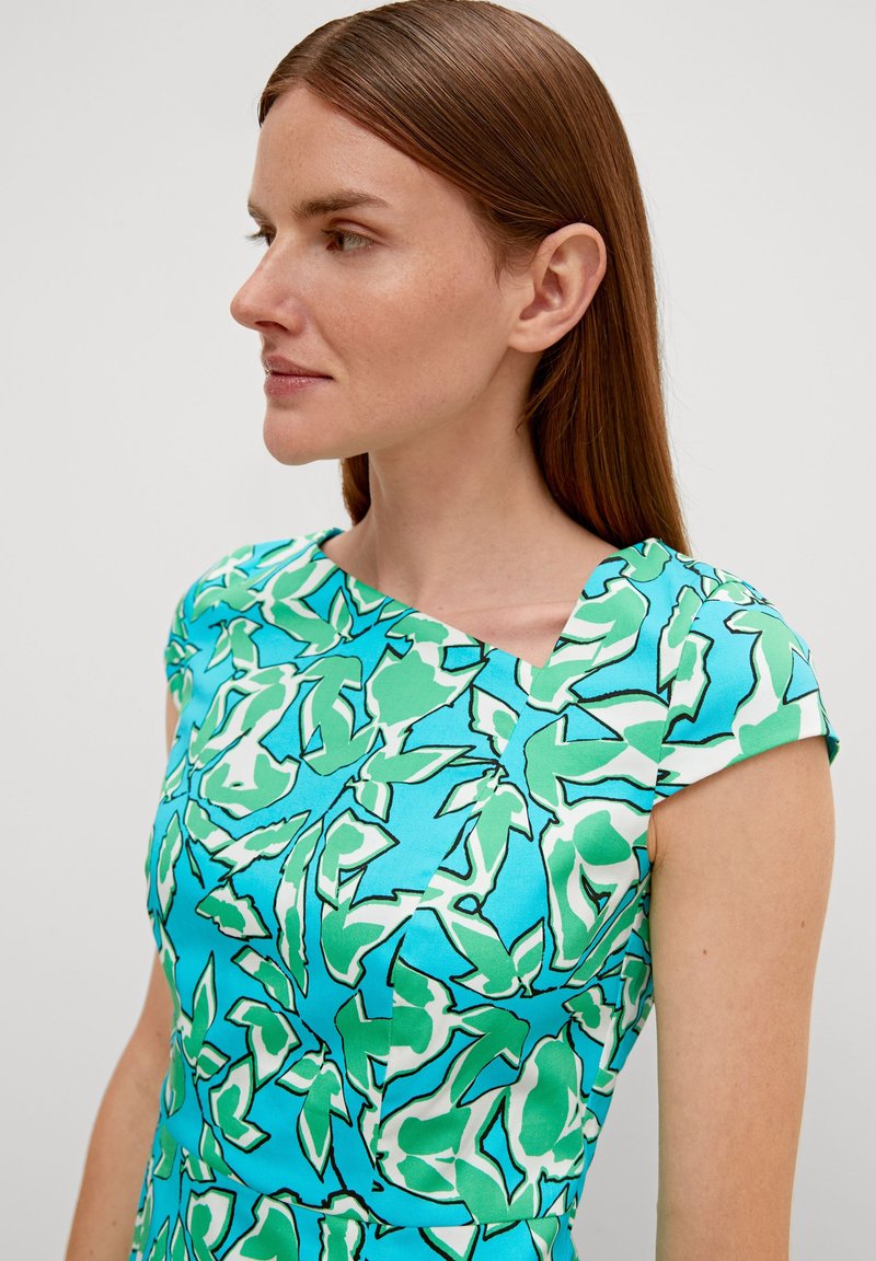 Kleid mit kurzen Ärmeln aus lebhaft blauer Stoff, verziert mit einem grünen und weißen Blumenmuster, das einen strukturierten Ausschnitt und eine glatte Textur aufweist.