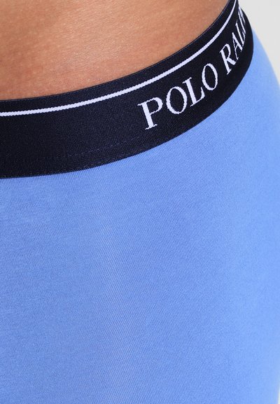 Lichtblauwe rekstof met een zwarte tailleband met witte "POLO RALPH LAUREN" branding, die een gladde textuur en een aansluitend ontwerp laat zien.