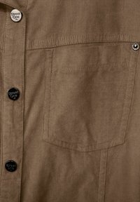 Camicia in corduroy marrone con una tasca sul petto, sei bottoni neri e sottili strisce testurizzate. Accompagnata da un logo "Street One".