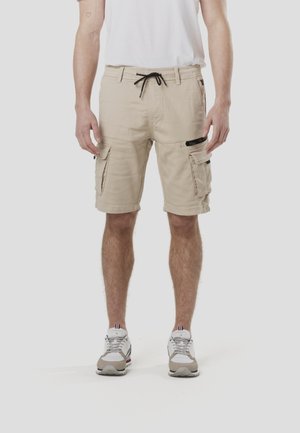 Bézs színű cargo rövidnadrág rugalmas derékpánttal és fekete zsinórral. Több oldalzsebbel rendelkezik, sima, pamutszerű textúrával.