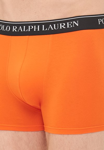 Oranžne bokserice z črnim pasom, na katerem je bel napis "POLO RALPH LAUREN." Mehka tkanina z tesnim prileganjem in minimalnimi šivi.