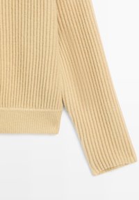 Beige ribbad tröja med långa ärmar, med en strukturerad stickad design och en enfärgad finish vid fållen och mudden.