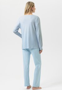 Vaaleansininen, pitkähihainen paita, jossa on rento istuvuus ja resoripinta, yhdistettynä saman sävyisiin, löysälahkeisiin housuihin.