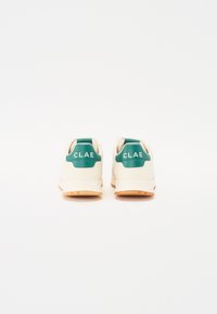 Cream-colored sneakers featuring a green leather heel cap with "CLAE" branding, complemented by a gum rubber sole.