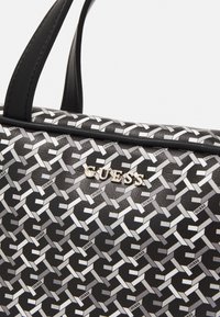 Borsa nera con un motivo geometrico di manici intrecciati in argento e un logo metallico prominente. Texture liscia con design strutturato.
