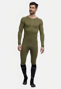 Olive green fitted thermal base layer with long sleeves and full-length leggings. Accented with black textured socks and reflective details.