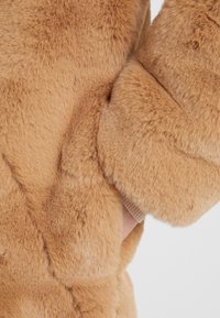 Faux-Fur-Mantel in Hellbraun mit weicher Textur, rundem Kragen und gerippten Bündchen sowie einer versteckten Seitentasche für praktischen Nutzen.