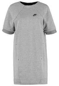 Grå sweatshirtklänning med korta ärmar, ribbad mudd och sidofickor. Har en svart Nike-logotyp på bröstet. Tillverkad av mjukt tyg.