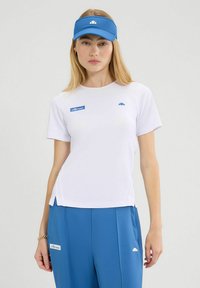 Camiseta blanca con acentos de logo azul, combinada con pantalones deportivos azules. La visera también es azul, con un diseño similar.