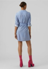 Kostkovaná modro-bílá košilová šaty s ohrnutými rukávy, opásaným pasem a délkou po kolena. Nalezeno s jasně růžovými platformovými botami a ponožkami.