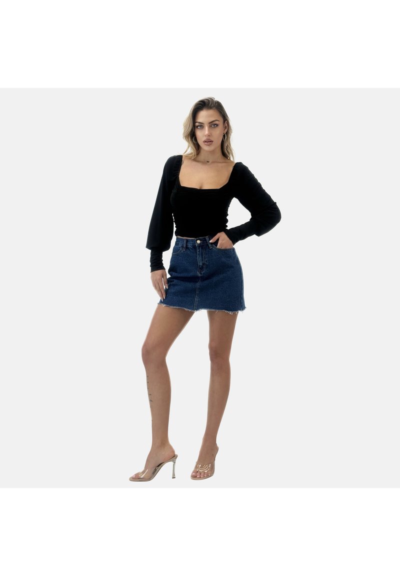 Top lungo nero a maniche lunghe con scollatura quadrata e dettagli arricciati, abbinato a una mini gonna in denim blu con orlo sfilacciato e sandali trasparenti con tacco.