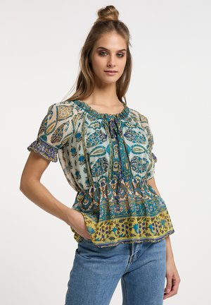 Blusa floreale leggera con maniche corte, scollo arricciato e orlo a peplo. Presenta intricati motivi blu, verdi e gialli.