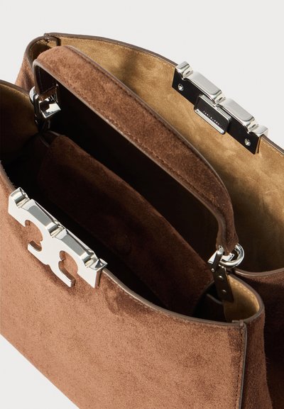 Bolsa de camurça castanha com fecho prateado, aberta para mostrar o forro interior suave em tom bege e um bolso interior de camurça a condizer.