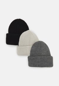 Three knit beanies in black, white, and gray. Each features a ribbed texture with a folded cuff at the base and a tapered top.