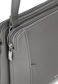 La borsa in pelle grigia presenta una superficie testurizzata, chiusure a zip duali e un accento in metallo con un'etichetta logo. Design compatto e strutturato.