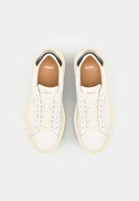 Sneakers bianche con tomaia in pelle liscia, suola in gomma color crema e dettaglio nero sul tallone. Presentano lacci piatti e logo impresso.