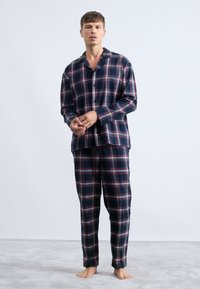 Conjunto de pijama de franela a cuadros en tonos azul marino, que incluye una camiseta de manga larga con cierre de botones y pantalones a juego con cintura elástica.