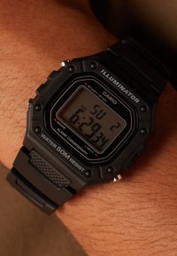 Digital watch with a black resin case and band, featuring a rectangular face, LCD display, water resistance to 50 meters, and visible buttons.