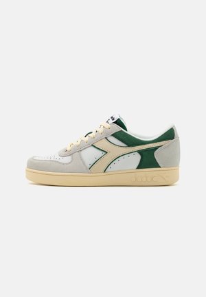White and green athletic sneaker featuring suede and leather materials, perforated toe, beige accents, and a rubber sole with logo.