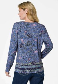 Langärmliges blaues Oberteil mit floralem Muster, runder Halslinie und abgerundetem Saum. Hergestellt aus weichem Stoff in verschiedenen Farben und mit strukturiertem Design.