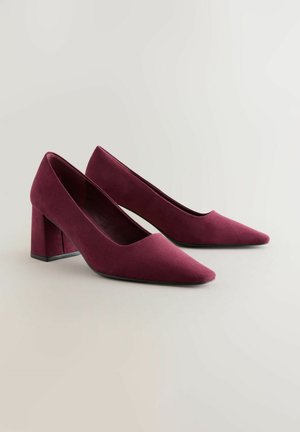 Scarpe con tacco in suede bordeaux con punta affusolata e tacco a blocco quadrato. Texture liscia con un design minimalista e senza accenti visibili.