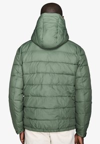 Grøn puffy jakke med vandret syninger, hætte og elastiske manchetter. Glat tekstur, isoleret, mellemlang design for varme.