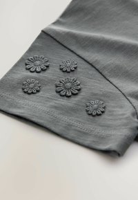 Grauer Stoff mit fünf dunkelgrauen gestickten Blumenmotiven am Saum der Ärmel, mit einer glatten Textur und einem sauberen Kantenfinish.