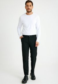 Zwarte broek met een rechte snit, gecombineerd met een witte blouse met lange mouwen. Soepele textuur, minimalistisch ontwerp, met een knoopsluiting en zijzakken.