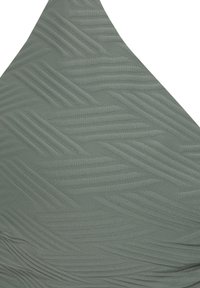Groene textuurstof met een zigzagpatroon, met een gladde afwerking en variërende reliëfdetails, gevormd in een driehoekig ontwerp.