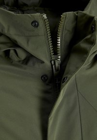 Olive green jacket featuring a full-length zipper, snap buttons, and a textured fabric with a smooth inner lining. No visible patterns.