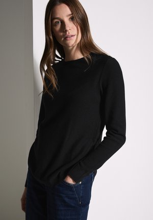 Black ribbed long-sleeve top with a crew neckline, paired with dark blue denim jeans. The fabric appears soft and casual in style.