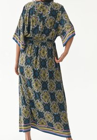 Musterkleid im Kimono-Stil in Grün, Blau und Lila. Mit einem elastischen Taillenbund, kurzen Ärmeln und gestreiften Akzenten am Saum.