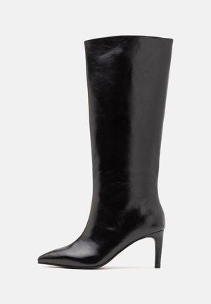 Botte en cuir noire montant jusqu'au genou avec bout pointu et talon fin de hauteur moyenne, présentée de profil sur un fond clair.